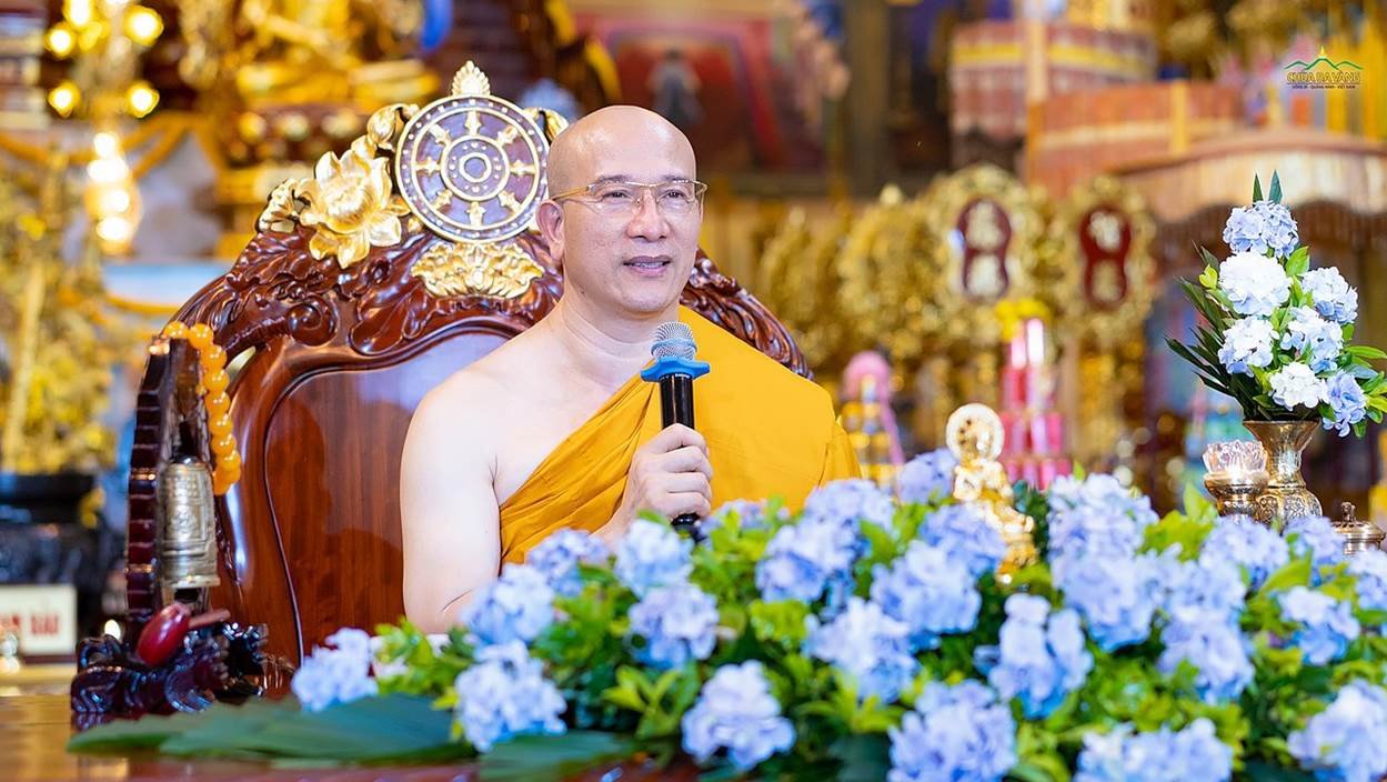 A person in a yellow robe holding a microphone
Description automatically generated